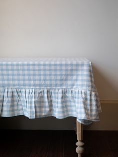 a blue and white checkered table cloth with ruffles on the top, sitting in front of a wall