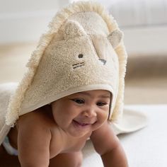 a baby is laying on his stomach wearing a towel with a lion face on it's head