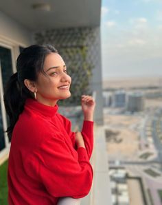 a woman standing on top of a building with her arms crossed and looking off into the distance