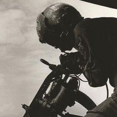 black and white photograph of a man on a motorcycle doing tricks in the air with his helmet up