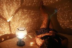 a woman laying on top of a bed next to a night stand with a lamp