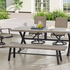 an outdoor dining table with four chairs and a bench in front of the patio area