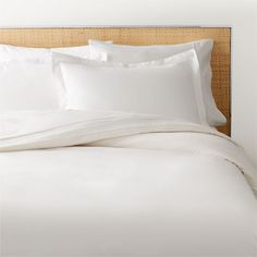 a bed with white sheets and pillows on it