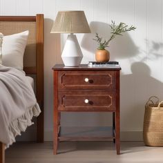 a nightstand with two drawers next to a bed and a basket on the floor in front of it