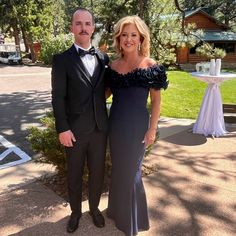 a man and woman standing next to each other in formal wear at an outdoor event