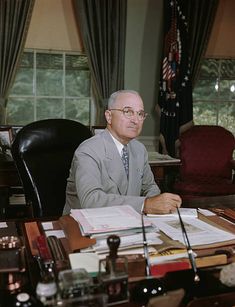 an older man sitting at his desk in the oval office with papers and pens on it