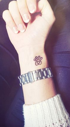 a woman's wrist with a small dog paw tattoo on it