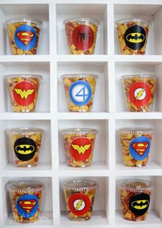 the cupcakes are decorated with superman and wonder logos on them, all in plastic cups