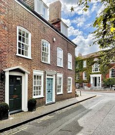 an old brick building with white windows and blue door on the side of the street