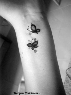 a black and white photo of a woman's arm with a butterfly tattoo on it