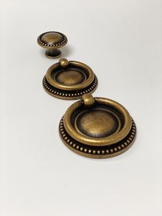 three antique brass knobs on a white surface