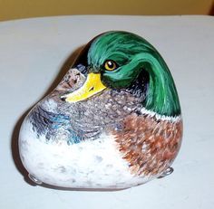 a painted rock shaped like a duck sitting on top of a table