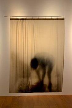 a blurry image of a person standing in front of a curtain on the wall