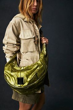 A bold way to carry it all, this slouchy sling is featured in a buttery soft leather with a metallic finish and shiny metal hardware. **Features:** Buttery soft leather with a metallic finish, zippered front pocket, top-zip closure, cotton-lined interior with zippered pocket, slouchy and unstructured, removeable shoulder strap **Why We | We The Free Sparta Sling Bag at Free People in Green Green Bag Outfit, Edgy Accessories, Free People Bags, Oversized Bag, Fringe Purse, Leather Sling Bag, Metallic Purse, Bohemian Accessories, Pull On Jeans