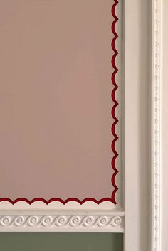 a red and white cat sitting on top of a window sill in front of a pink wall