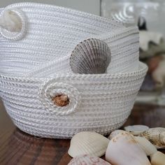 a white basket sitting on top of a wooden table next to shells and seashells