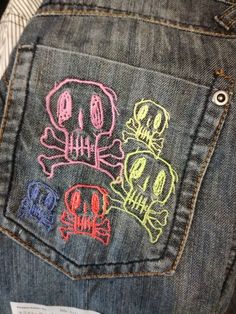 the back pocket of someone's jean pants with embroidered skulls on them and bones in different colors