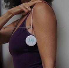 a woman holding onto a string with a button on it's end and wearing a purple tank top