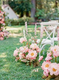 pink flowers and greenery are arranged in rows on the grass next to a white chair