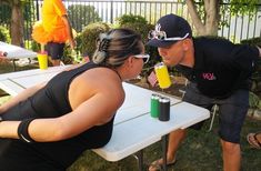 a man and woman standing next to each other at a table with drinks in front of them