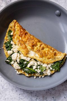 an omelet with spinach and feta cheese in a gray plate on a marble table