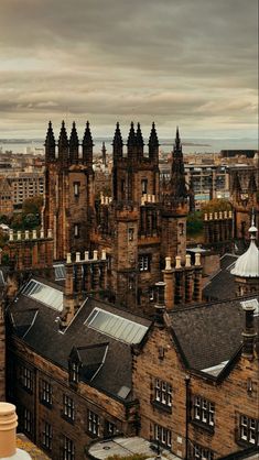 an aerial view of old buildings in the city with cloudy skies behind them, including tall towers