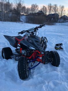 an atv is parked in the snow next to a sled and other things on the ground