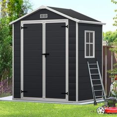 a small black shed sitting in the grass next to a lawn mower and ladder