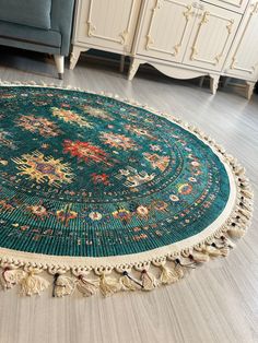 a round rug with tassels on the floor in front of a blue couch