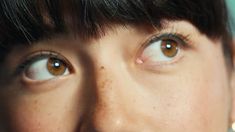 a woman's face with brown eyes and short black hair is seen in this image