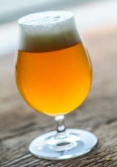 a glass filled with liquid sitting on top of a wooden table