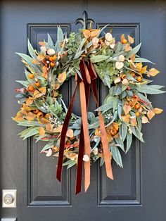 a wreath on the front door with orange and green flowers hanging from it's side