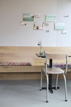 two wooden benches sitting next to each other in front of a wall with pictures on it