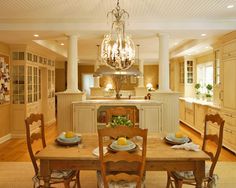 a dining room table and chairs with plates on them in front of a chandelier