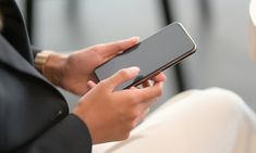 a close up of a person holding a cell phone in their hands and typing on the screen