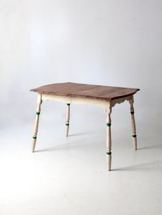 a small wooden table with green legs on a white background