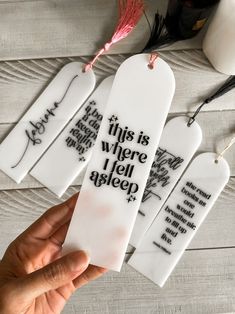 three white bookmarks with black writing on them, one has a pink tassel