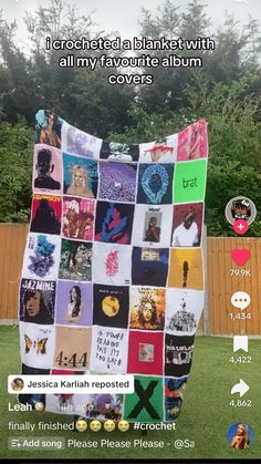 a large blanket covered in pictures on top of a grass field next to a wooden fence