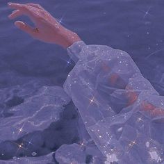 a hand reaching out to the water with sparkling stars on its body and in front of it