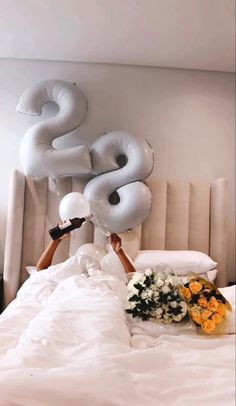 a woman laying in bed with flowers and balloons