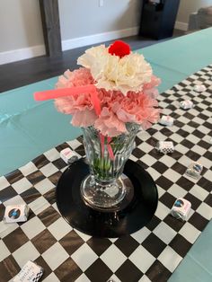 a vase filled with pink and white flowers on top of a checkered table cloth