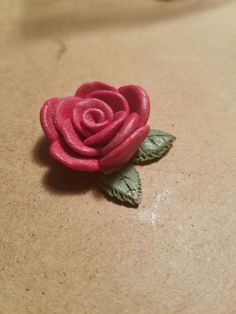 a small pink rose sitting on top of a brown table next to a green leaf