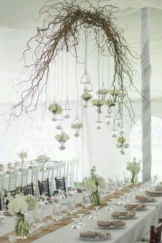 the table is set up with white flowers and greenery hanging from it's ceiling