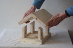 someone is building a wooden birdhouse on top of a table