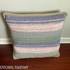 a crocheted pillow sitting on top of a wooden floor next to a wall