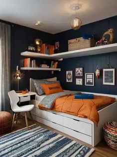 a bedroom with blue walls and white shelving, an orange bed spread on the floor