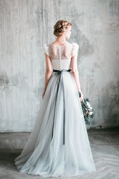 a woman in a wedding dress standing against a wall with her back to the camera