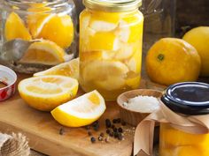 jars filled with lemons sitting on top of a cutting board next to other fruit