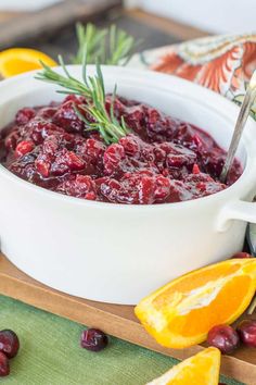 cranberry sauce in a white bowl with orange slices and rosemary sprigs