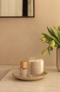 a candle and some flowers sitting on a bathroom counter next to a vase with tulips in it